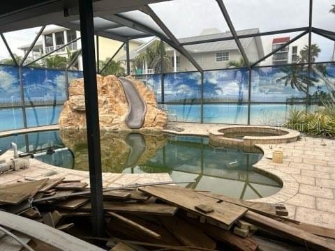 view of swimming pool featuring glass enclosure, a patio, and a pool with connected hot tub