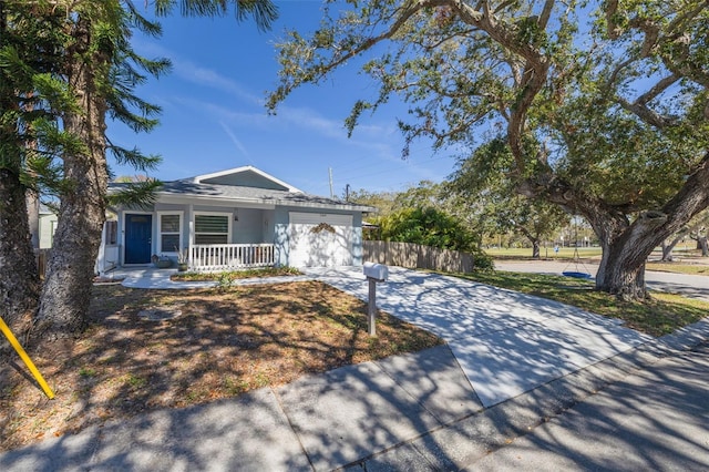 single story home featuring stucco siding, a porch, concrete driveway, fence, and a garage