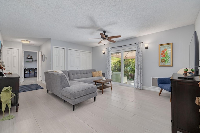 living room featuring ceiling fan, a textured ceiling, and baseboards