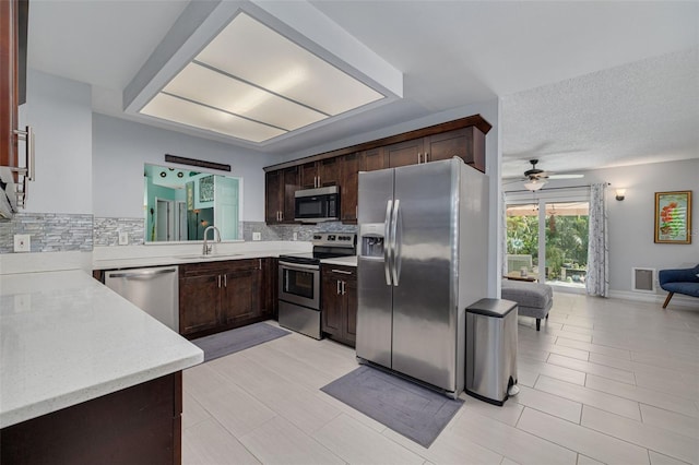 kitchen with dark brown cabinetry, stainless steel appliances, a sink, and light countertops