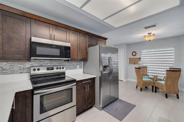 kitchen featuring dark brown cabinets, appliances with stainless steel finishes, light countertops, and tasteful backsplash