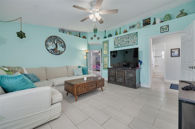 living room featuring ceiling fan, visible vents, and a textured ceiling