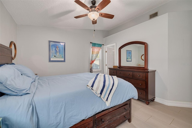 bedroom with lofted ceiling, visible vents, a textured ceiling, and light wood finished floors