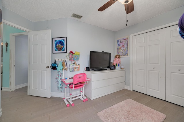 playroom featuring visible vents, a textured ceiling, baseboards, and a ceiling fan