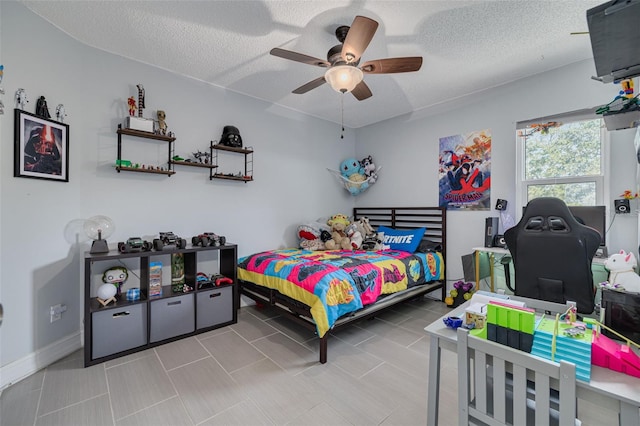 bedroom with a ceiling fan, a textured ceiling, and baseboards