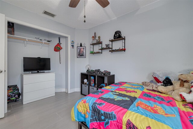 bedroom with a textured ceiling, ceiling fan, visible vents, and baseboards