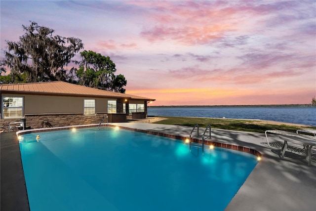 outdoor pool with a patio area and a water view