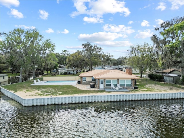 back of property with a water view, fence, and a chimney