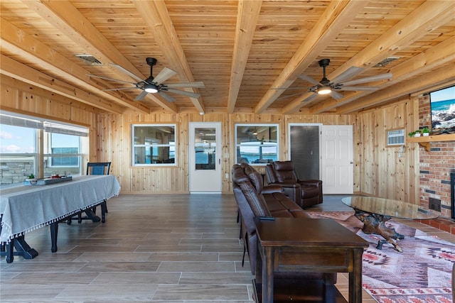 living room with ceiling fan, wood walls, and beam ceiling