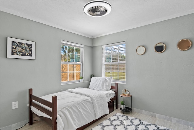 bedroom with ornamental molding, visible vents, baseboards, and wood finished floors