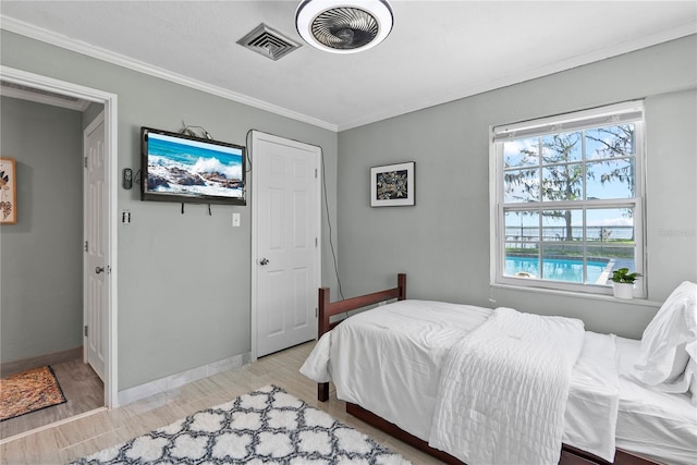 bedroom with crown molding, wood finished floors, visible vents, and baseboards