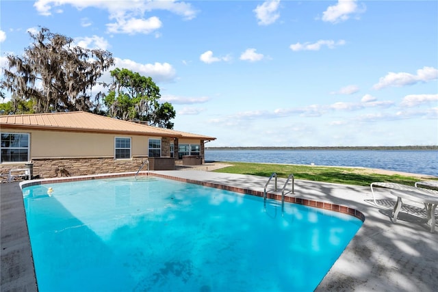 outdoor pool with a water view and a patio