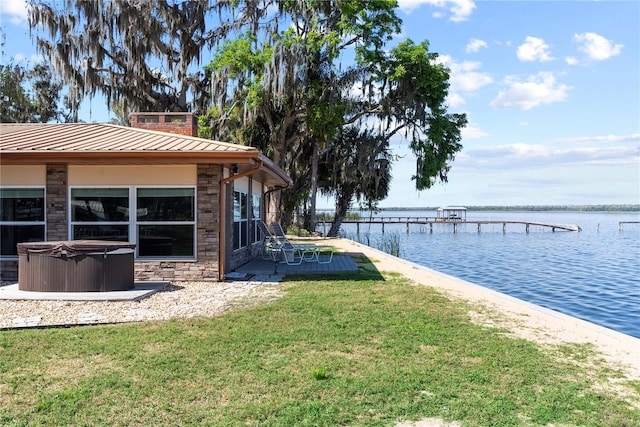 view of yard with a dock, a water view, and a hot tub