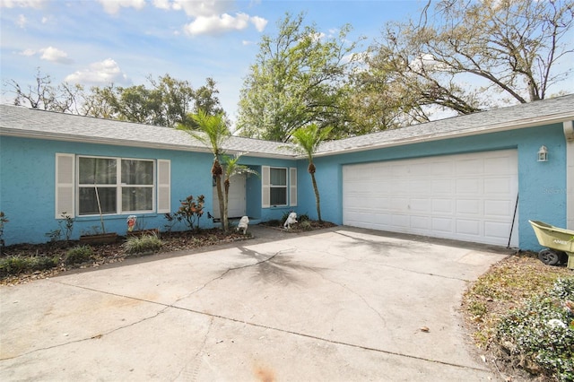 ranch-style home with stucco siding, an attached garage, concrete driveway, and roof with shingles