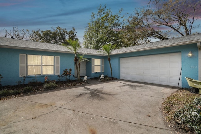 single story home with roof with shingles, a garage, driveway, and stucco siding