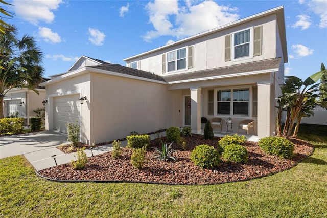 traditional-style house with driveway, a front yard, an attached garage, and stucco siding