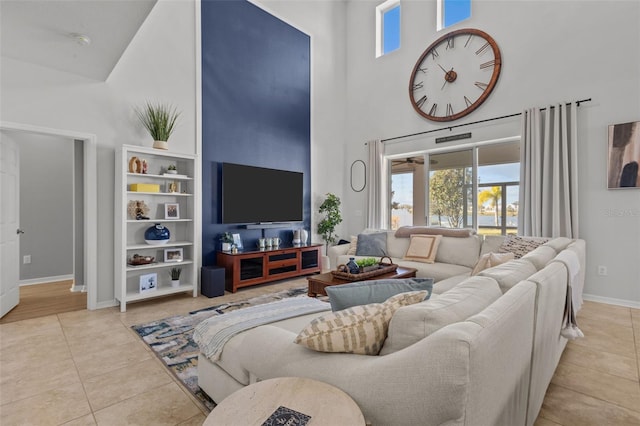 living area featuring tile patterned flooring, baseboards, and a high ceiling