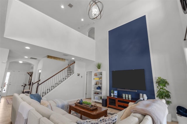 living room featuring visible vents, arched walkways, a towering ceiling, stairs, and recessed lighting