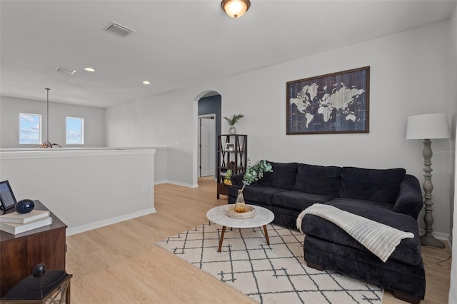 living area featuring arched walkways, recessed lighting, visible vents, baseboards, and light wood-type flooring