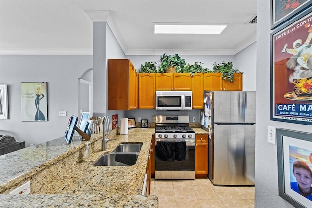 kitchen featuring ornamental molding, appliances with stainless steel finishes, a sink, and light stone counters