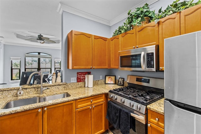 kitchen featuring stainless steel appliances, ornamental molding, a sink, ceiling fan, and light stone countertops