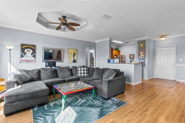 living area featuring arched walkways, crown molding, light wood finished floors, visible vents, and baseboards