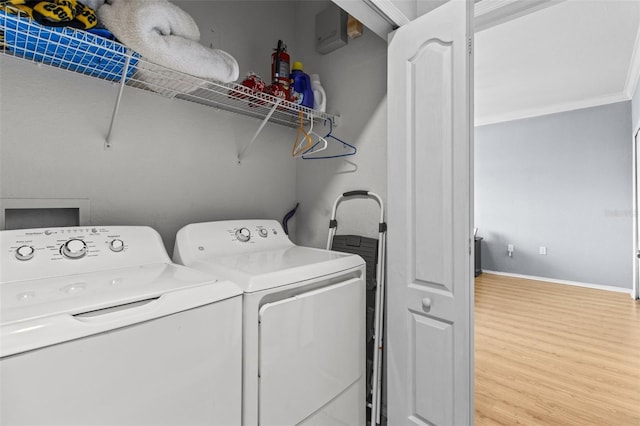 washroom with ornamental molding, laundry area, washing machine and clothes dryer, and wood finished floors