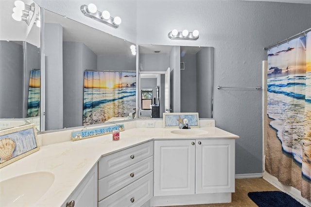 full bathroom featuring double vanity, a shower with curtain, a sink, and a textured wall