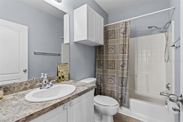 bathroom with a textured wall, toilet, vanity, tile patterned floors, and shower / bath combo with shower curtain