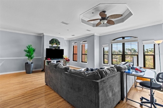 living room featuring a ceiling fan, visible vents, light wood-style floors, a tray ceiling, and crown molding