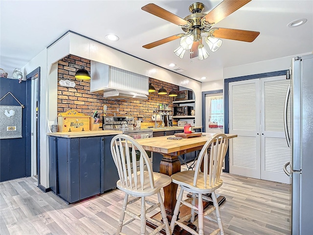 dining space featuring light wood-style floors, recessed lighting, and brick wall