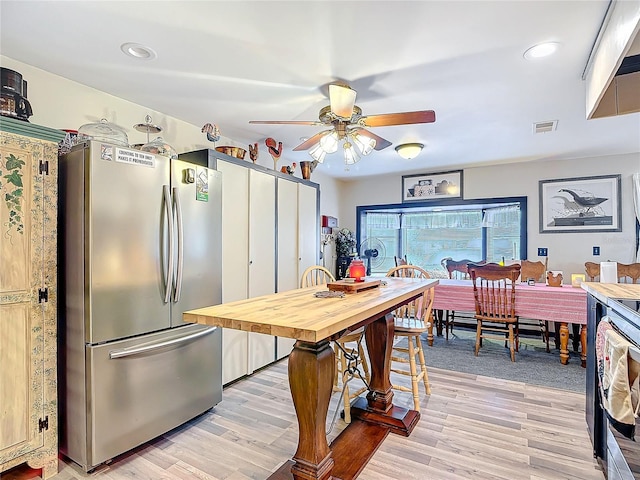 kitchen featuring a ceiling fan, freestanding refrigerator, visible vents, and light wood-style flooring