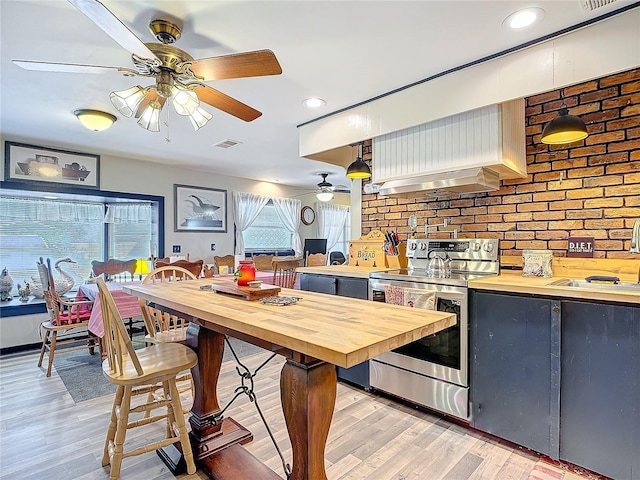 kitchen with light wood-style flooring, butcher block counters, a sink, visible vents, and stainless steel electric stove