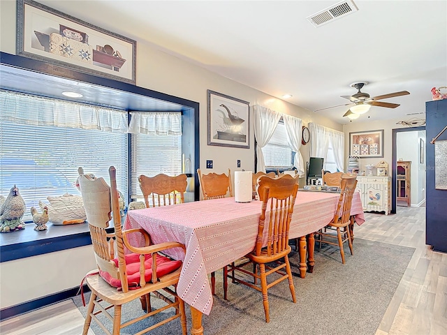 dining room with ceiling fan, light wood finished floors, visible vents, and baseboards