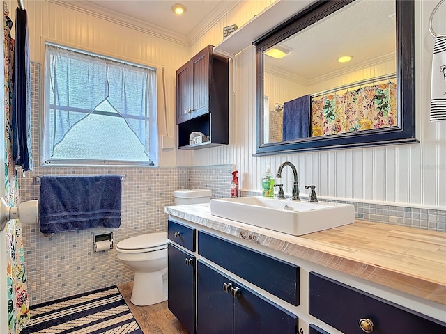 bathroom with toilet, ornamental molding, tile walls, and vanity