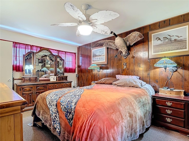 carpeted bedroom with ceiling fan and wooden walls