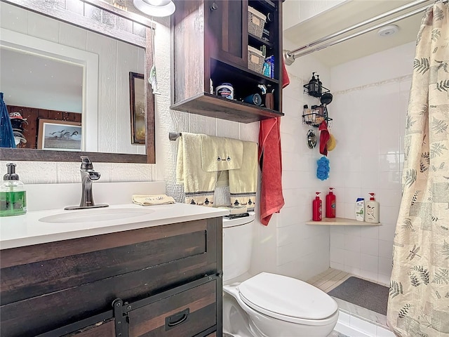 bathroom with toilet, tiled shower, and vanity