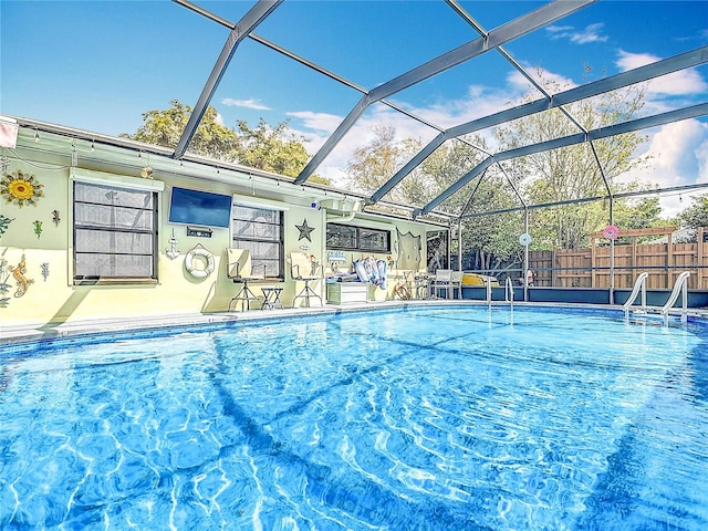 view of swimming pool featuring a patio area, fence, a fenced in pool, and a lanai