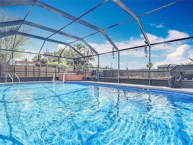 view of swimming pool featuring fence and a lanai