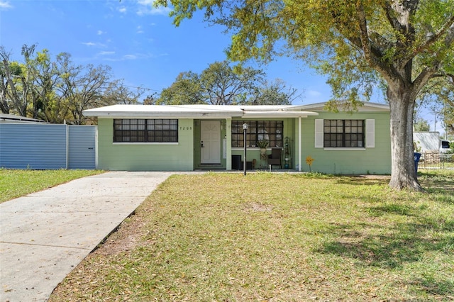 view of front of house with driveway, a front yard, concrete block siding, and fence