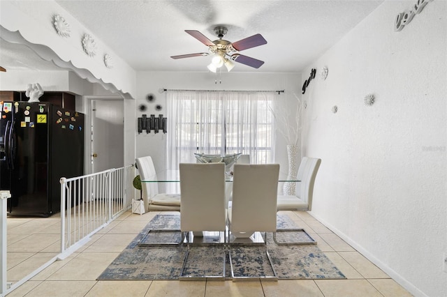 tiled dining area with a textured ceiling, baseboards, a ceiling fan, and a textured wall