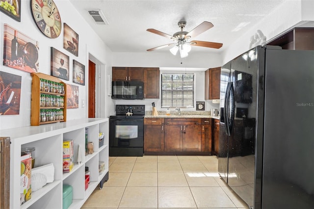 kitchen with light tile patterned floors, light countertops, visible vents, a sink, and black appliances