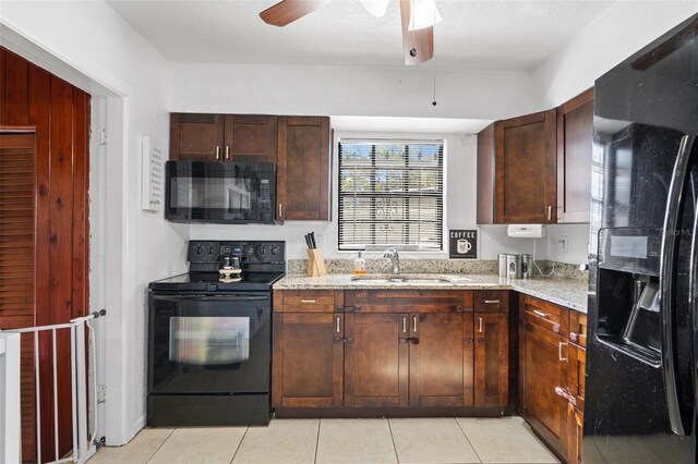 kitchen with light stone counters, light tile patterned floors, a sink, ceiling fan, and black appliances