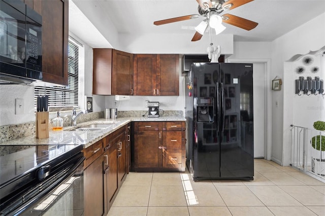 kitchen with light tile patterned flooring, a sink, black appliances, and light stone countertops