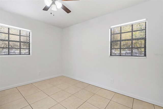 spare room featuring a ceiling fan, a healthy amount of sunlight, baseboards, and light tile patterned floors