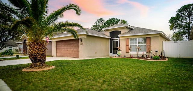 ranch-style house with driveway, a garage, stucco siding, fence, and a front yard