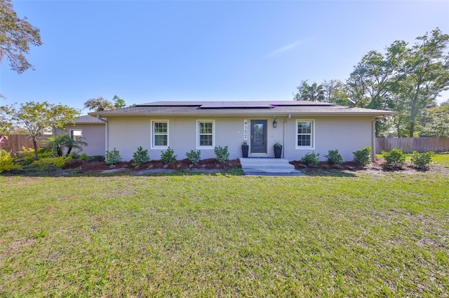 single story home with stucco siding, solar panels, and fence