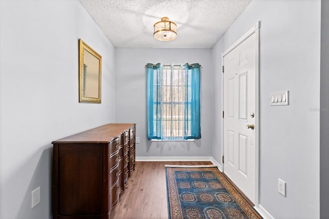 entryway with a textured ceiling, baseboards, and wood finished floors