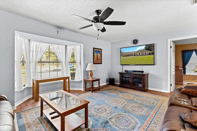 living room featuring a textured ceiling, wood finished floors, a ceiling fan, and baseboards