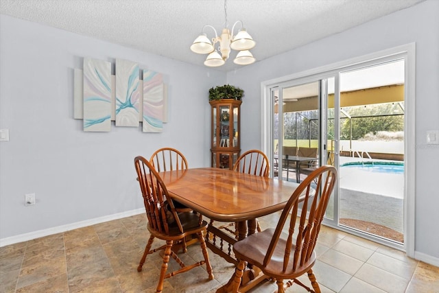 dining area with a textured ceiling, a chandelier, and baseboards